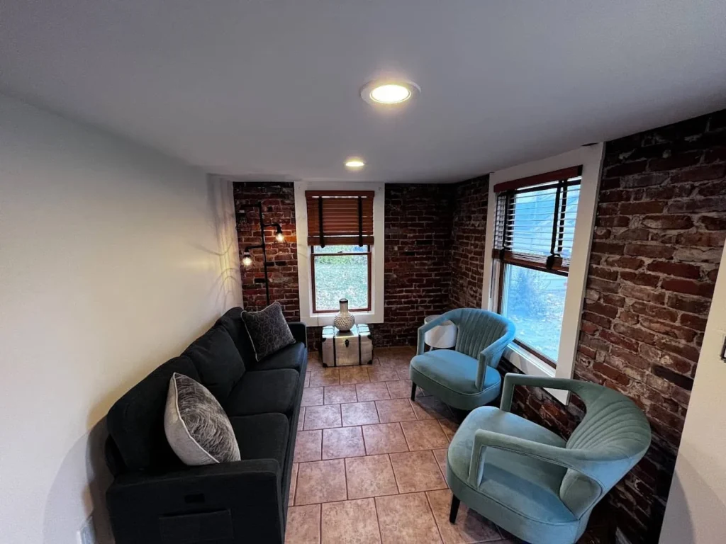 Living room with light painted walls, exposed brick and blue accent chairs